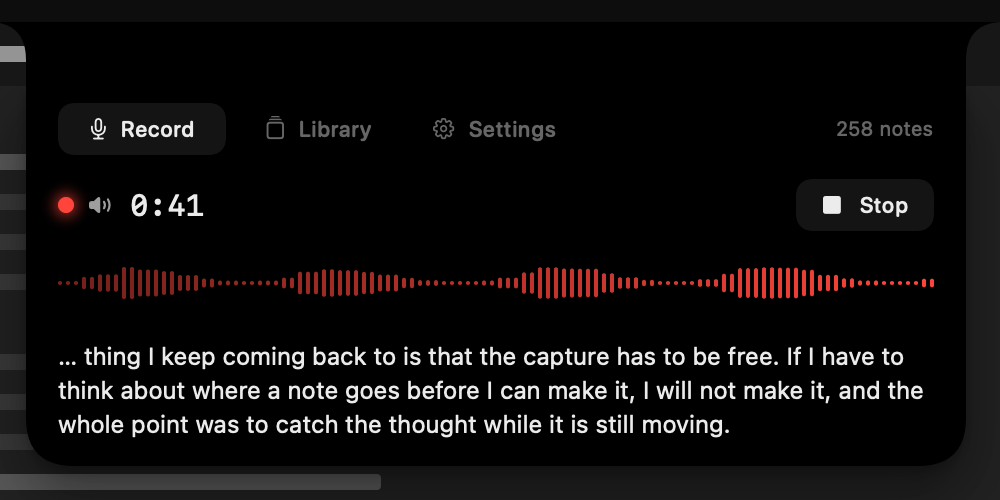 A recording panel opened out of a MacBook's camera notch, showing a live transcript as someone speaks.
